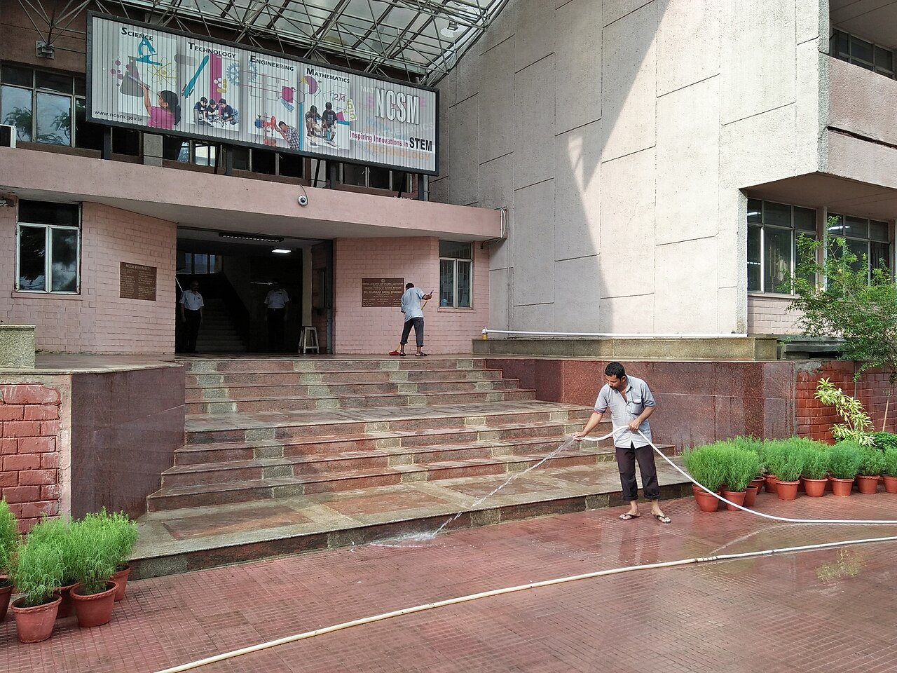 Nhân viên vệ sinh khu vực sân trước toà nhà văn phòng